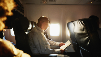Person reading a book on an aeroplane