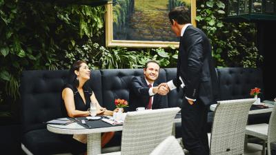 Smiling businessmen shaking hands before sitting down at table for meeting with business executives in restaurant