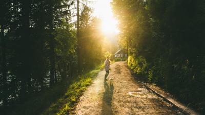 Young woman with long hair in striped shirt and her small fluffy pug enjoying summer colourful sunset at the countryside of Slovenia, Europe