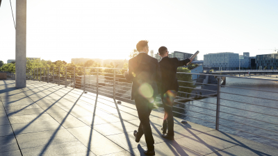 Two people in suits walking beside a river