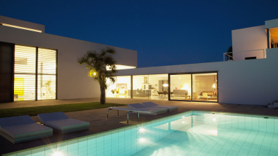 Luxurious modern home with illuminated swimming pool at night