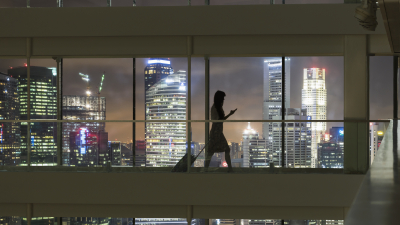 Person walking with a suitcase with a cityscape backdrop at night